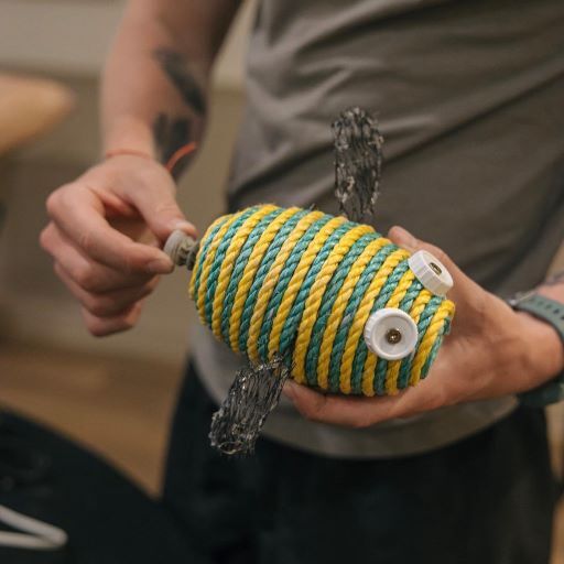 a set of hands holds onto the almost-finished bee, adding a bottle cap to the end to make a stinger.